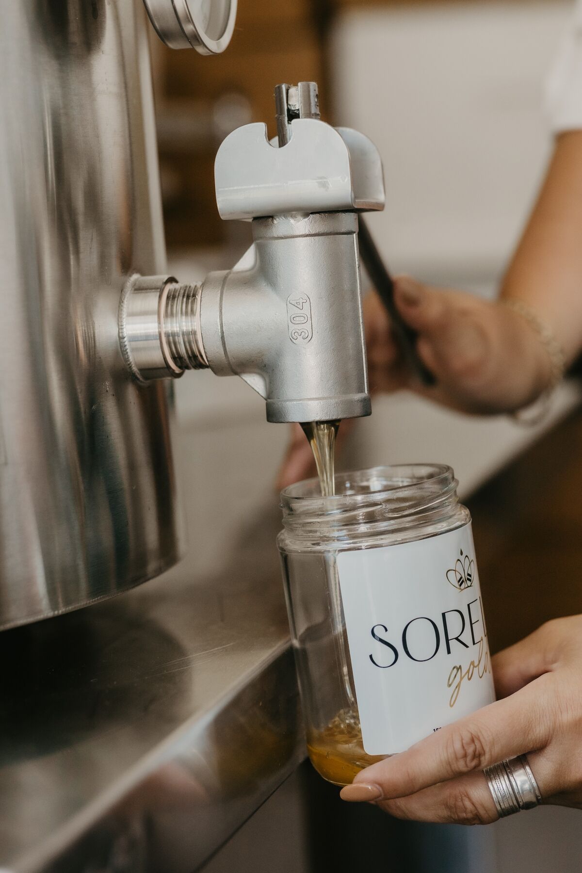 Raw honey pouring from the extractor tap into a Sorella Gold jar